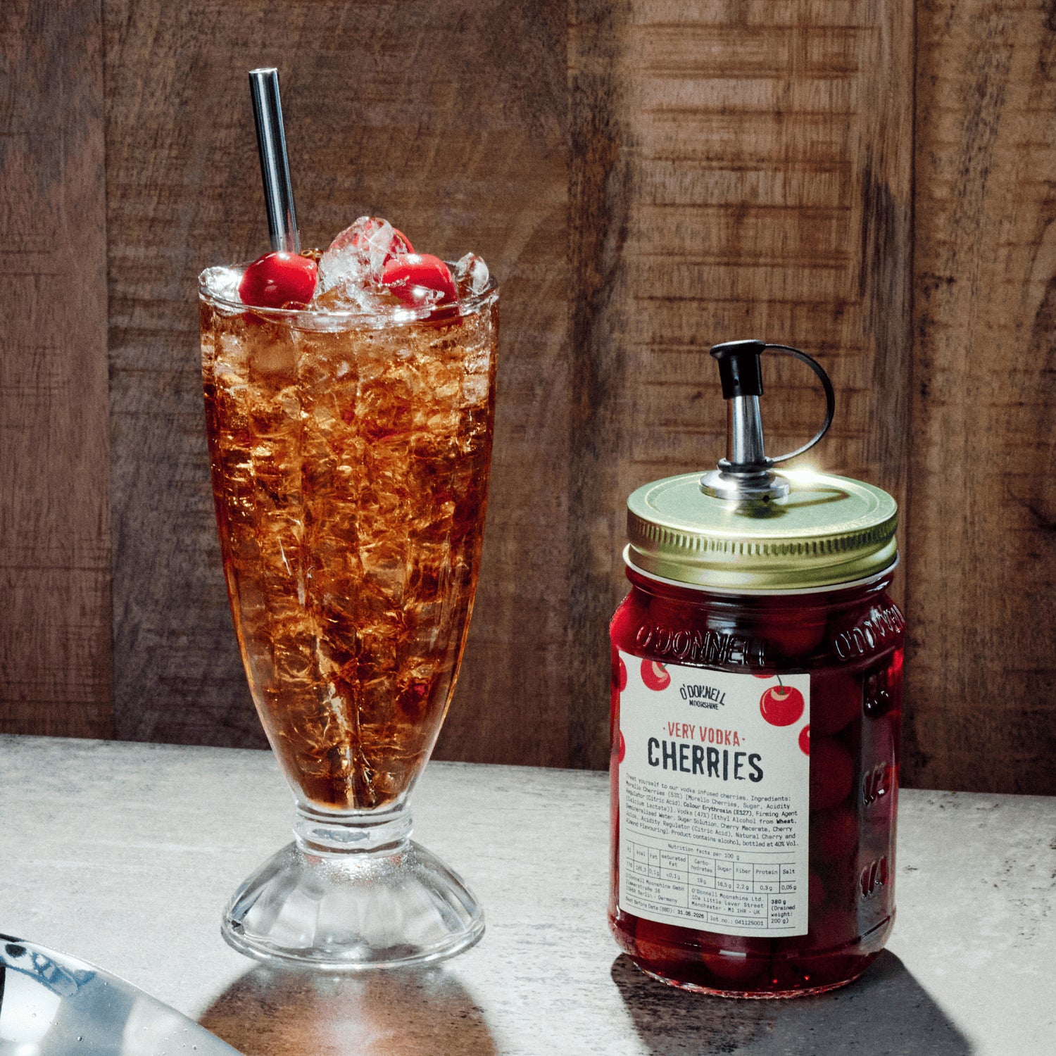 Very Vodka Cherries with a pouring lid attached next to a iced cola drink