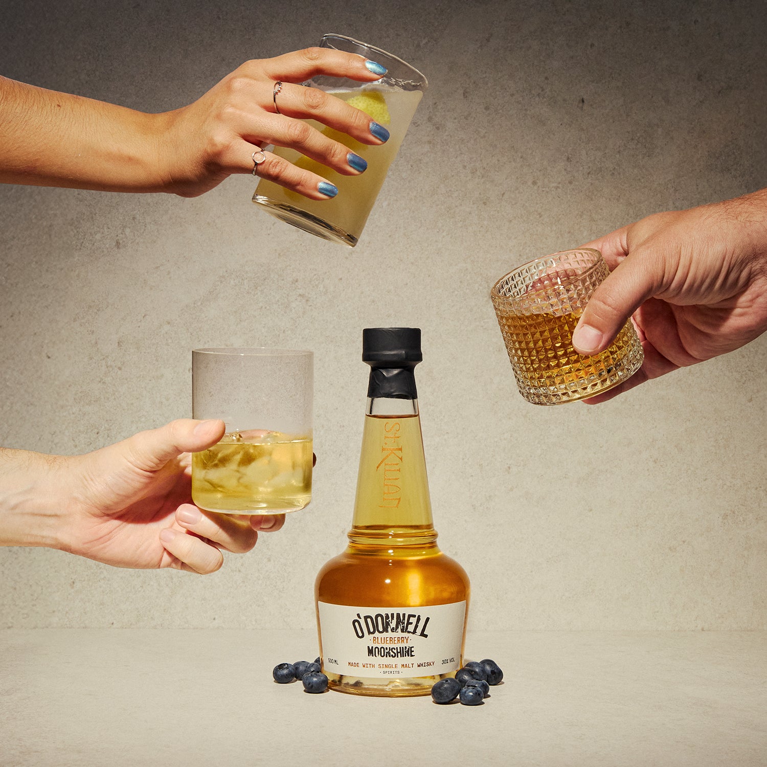 Bottle of O'Donnell Mustard with people holding glasses on a textured surface.