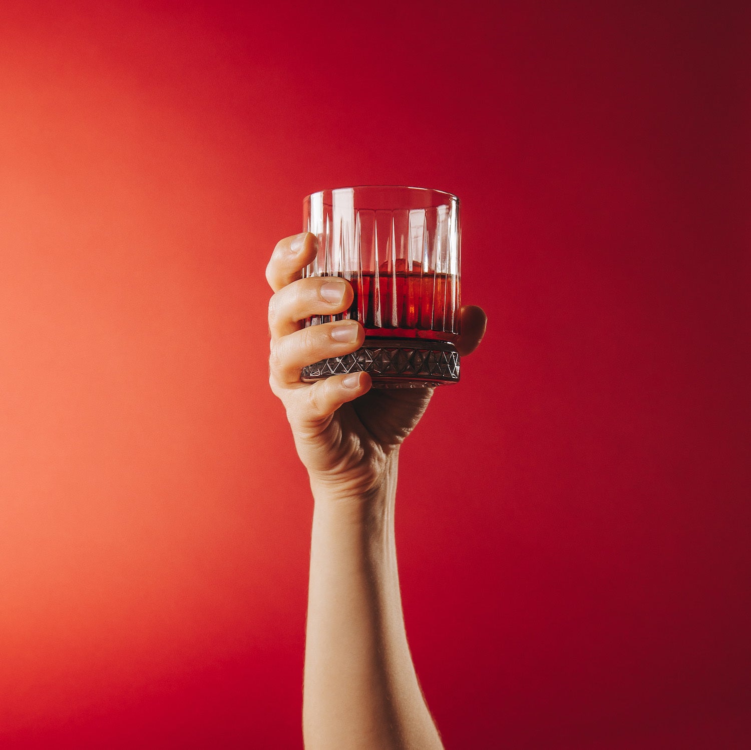 Strawberry & Rhubarb in a glass being held up with a red background