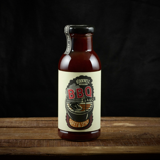 Bottle of BBQ sauce with a label on a wooden surface and black background