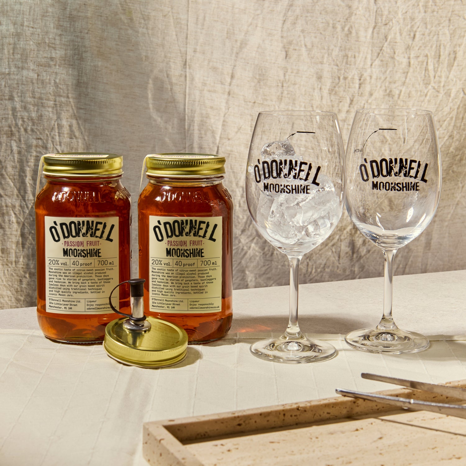 Two O'Donnell Sprit Glasses next to 2 700ml Jars of Passion Fruit Moonshine and a pouring lid