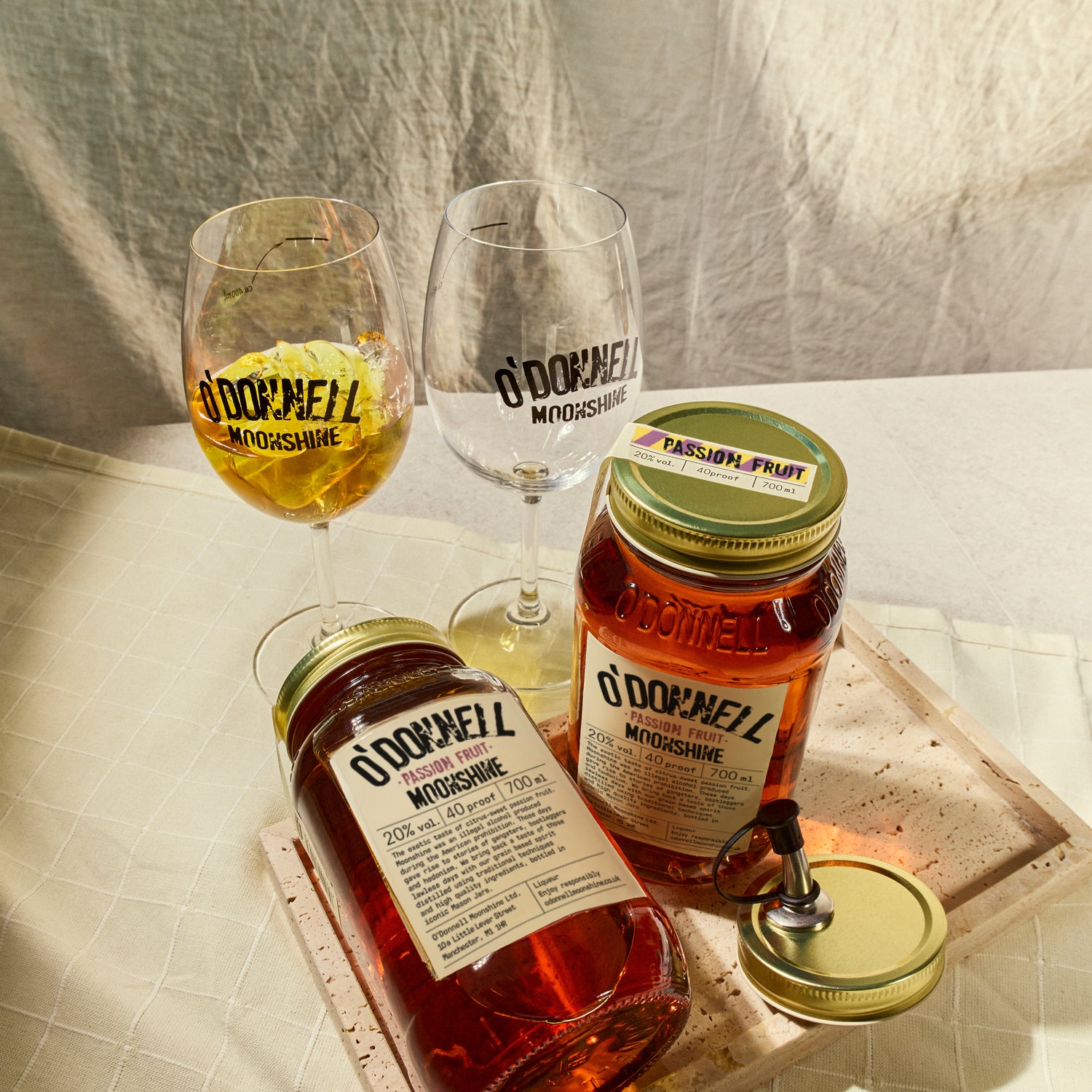 Two O'Donnell Sprit Glasses next to 2 700ml Jars of Passion Fruit Moonshine and a pouring lid