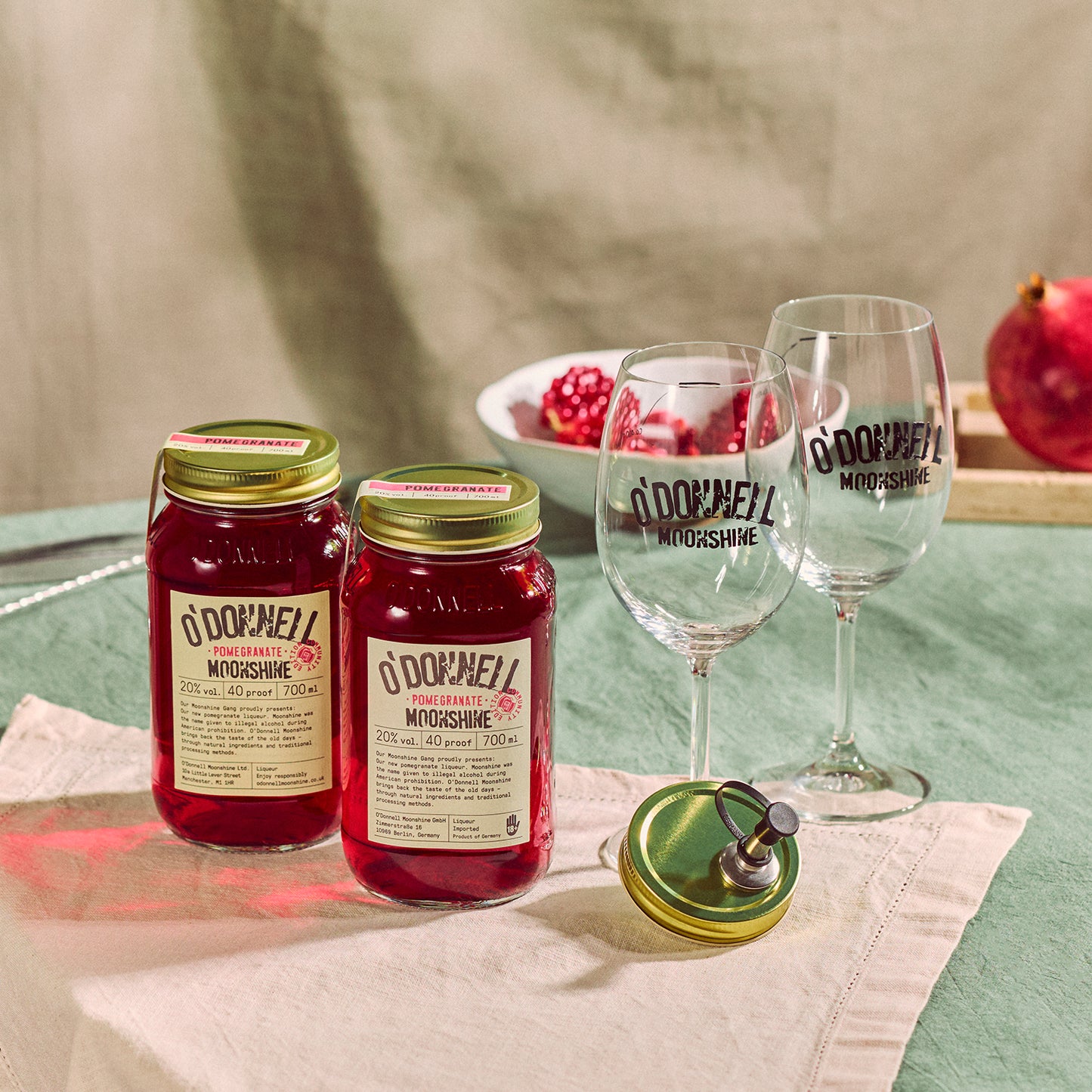 Two O'Donnell Sprit Glasses next to 2 700ml Jars of Pomegranate Moonshine and a pouring lid
