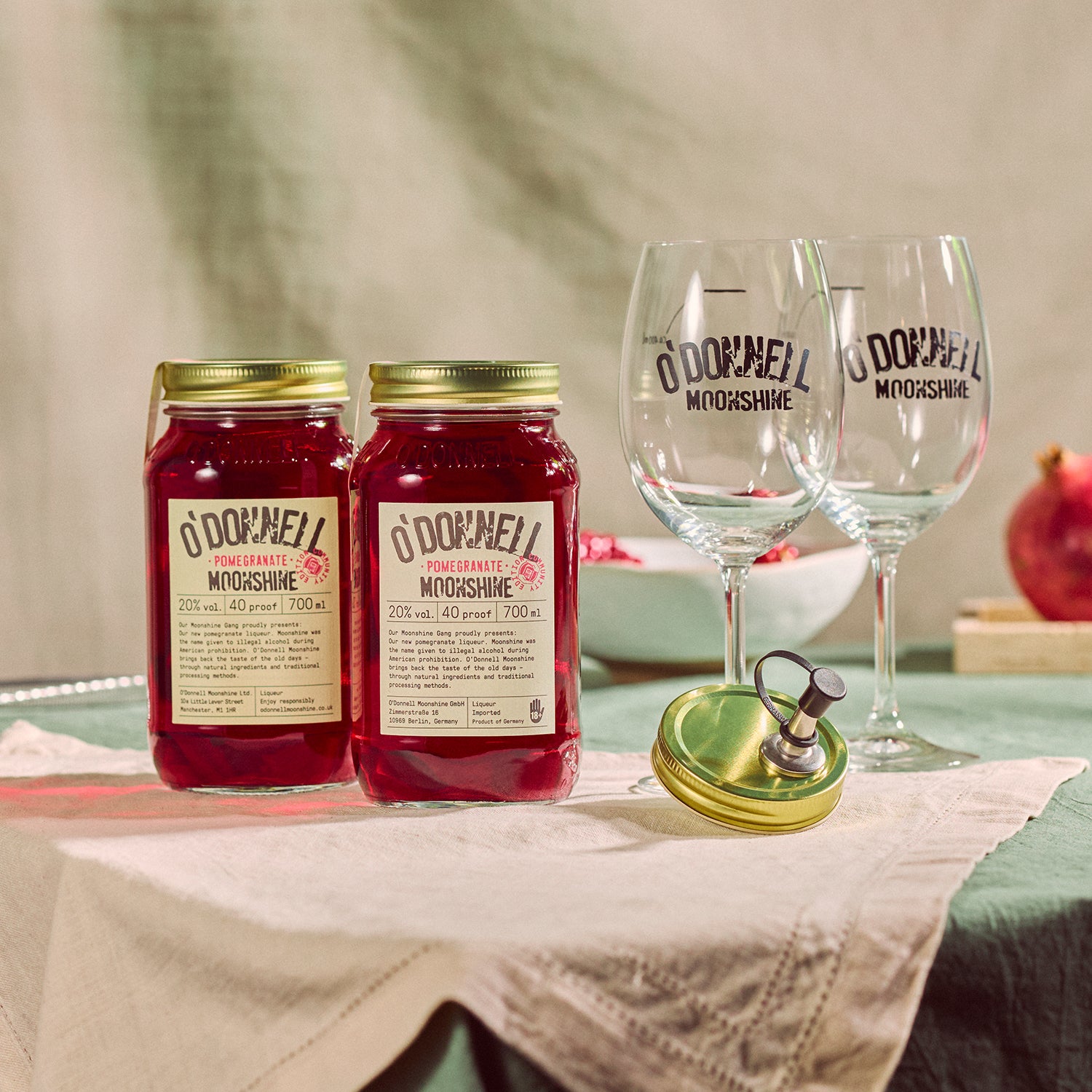 Two O'Donnell Sprit Glasses next to 2 700ml Jars of Pomegranate Moonshine and a pouring lid