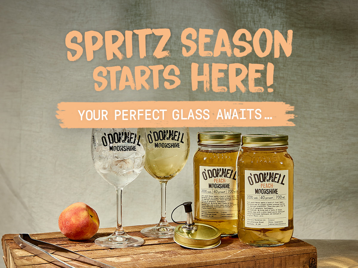 Spritz Season starts here. Your Perfect Glass Awaits, 2 peach moonshine jars, 2 spritz glasses and pouring lid on a wooden tray