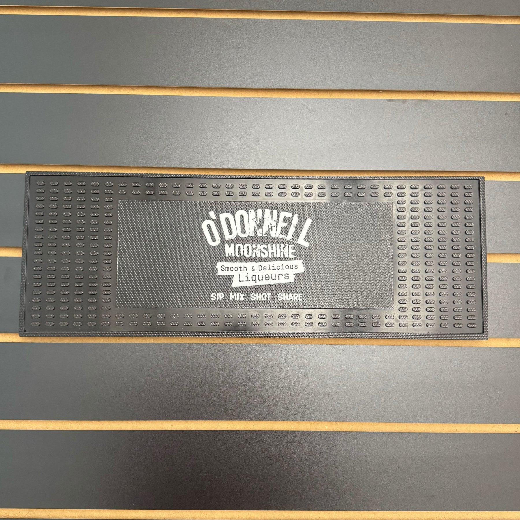 Black bar mat with 'O'Donnell Moonshine' branding on a wooden surface.