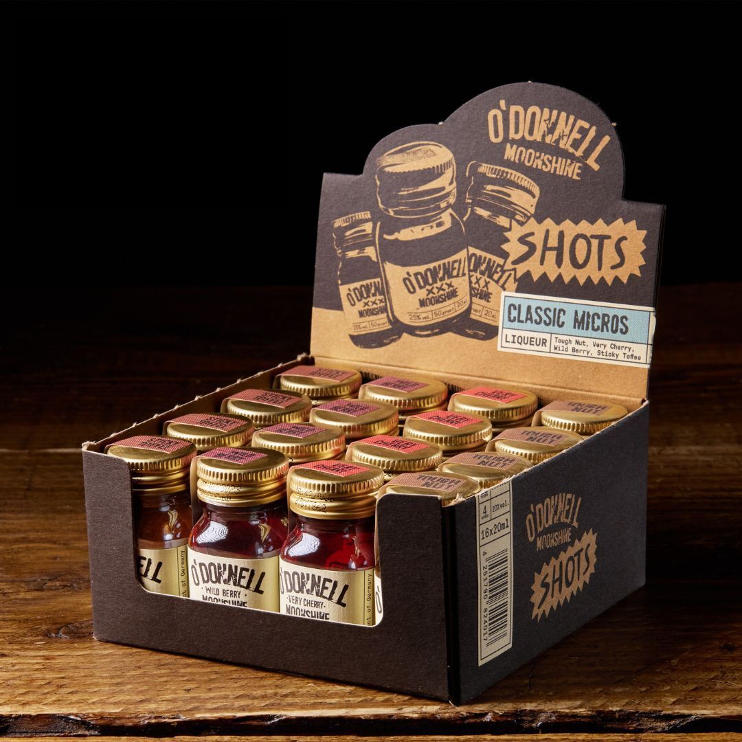 A box of O'Donnell Micro Moonshine shots displayed on a wooden surface, with each shot filled in a small Mason jar.