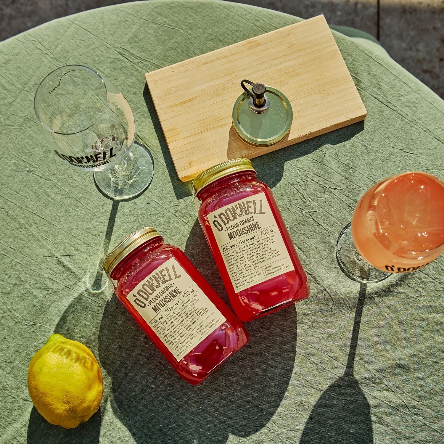 Two O'Donnell Sprit Glasses next to 2 700ml Jars of Blood Orange Moonshine and a pouring lid