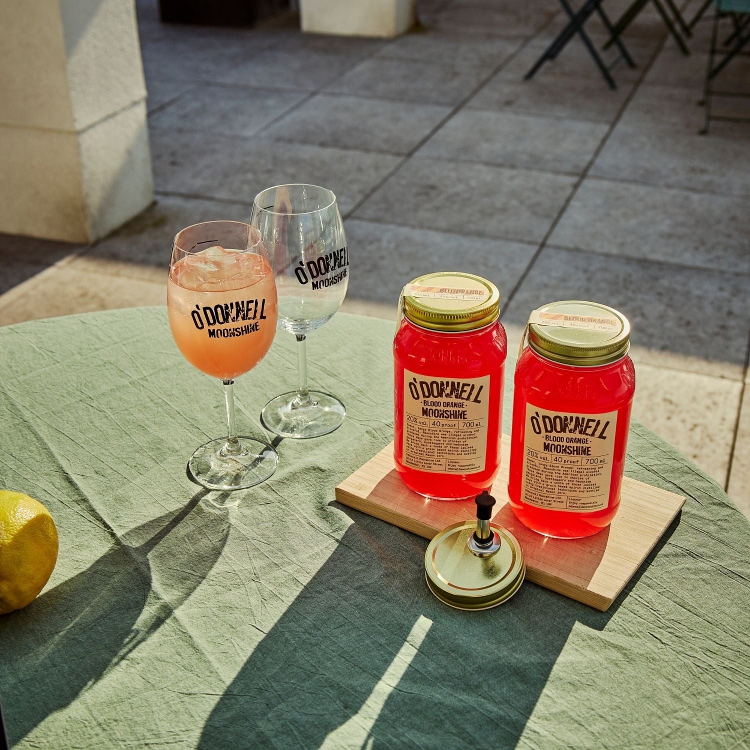 Two O'Donnell Sprit Glasses next to 2 700ml Jars of Blood Orange Moonshine and a pouring lid