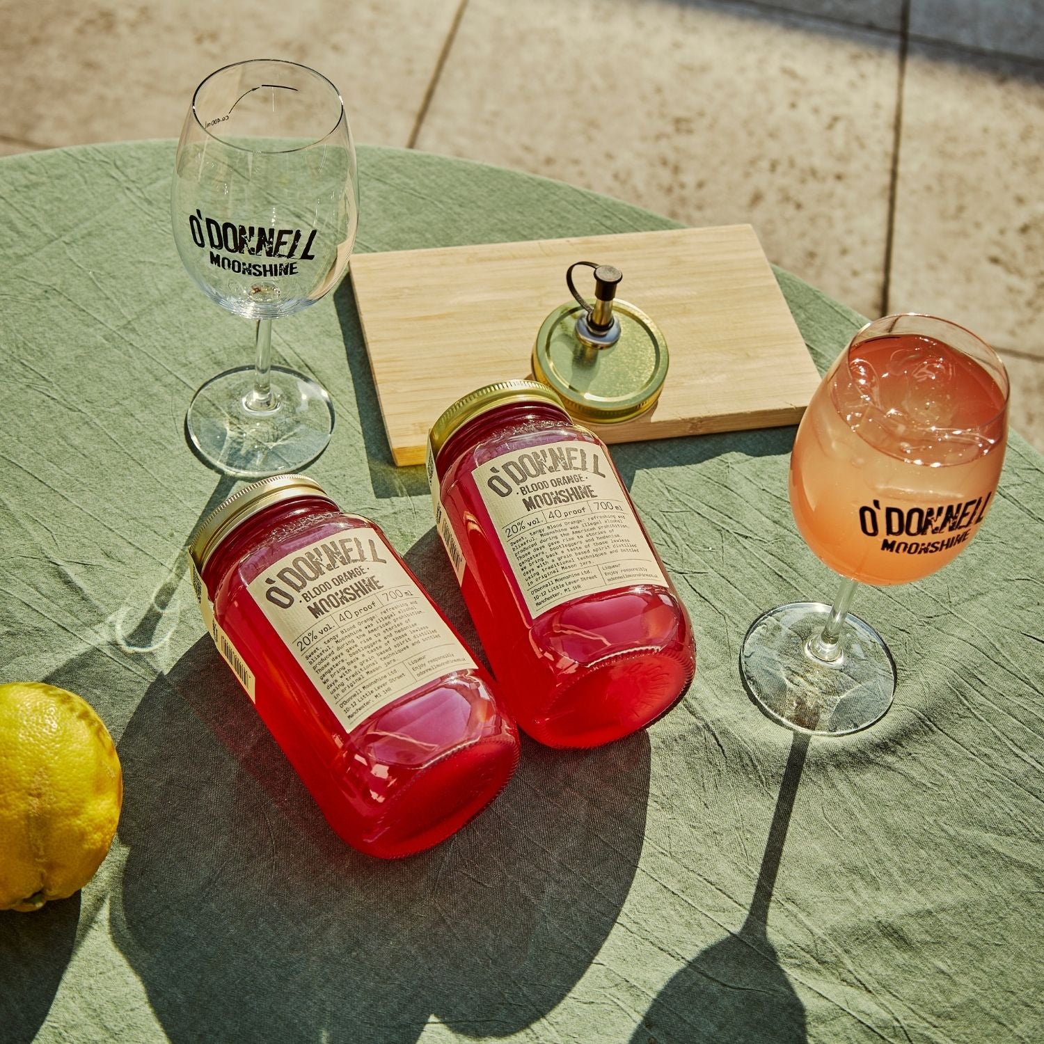 Two O'Donnell Sprit Glasses next to 2 700ml Jars of Blood Orange Moonshine and a pouring lid