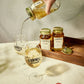 Two O'Donnell Sprit Glasses next to 2 700ml Jars of Peach Moonshine and a pouring lid. One is being poured