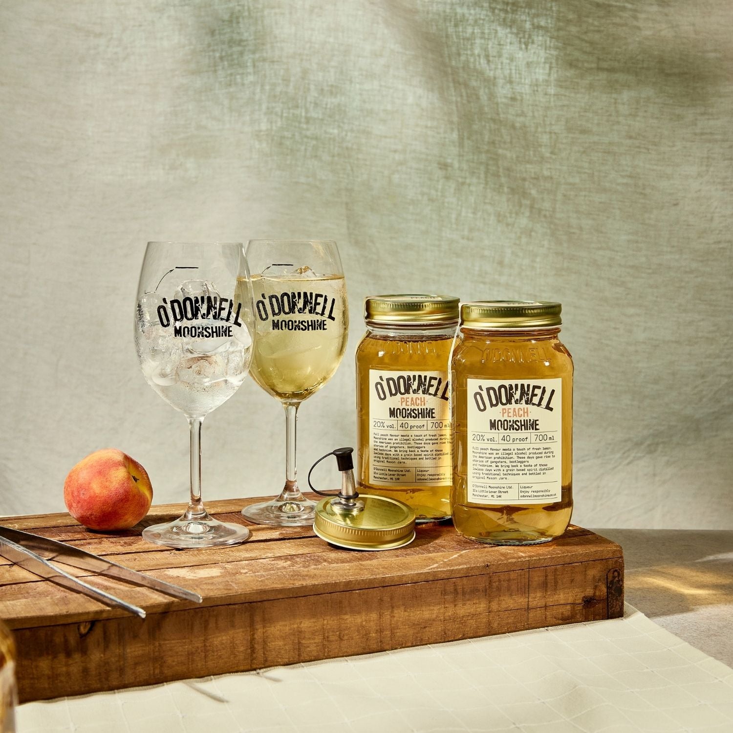 Two O'Donnell Sprit Glasses next to 2 700ml Jars of Peach Moonshine and a pouring lid