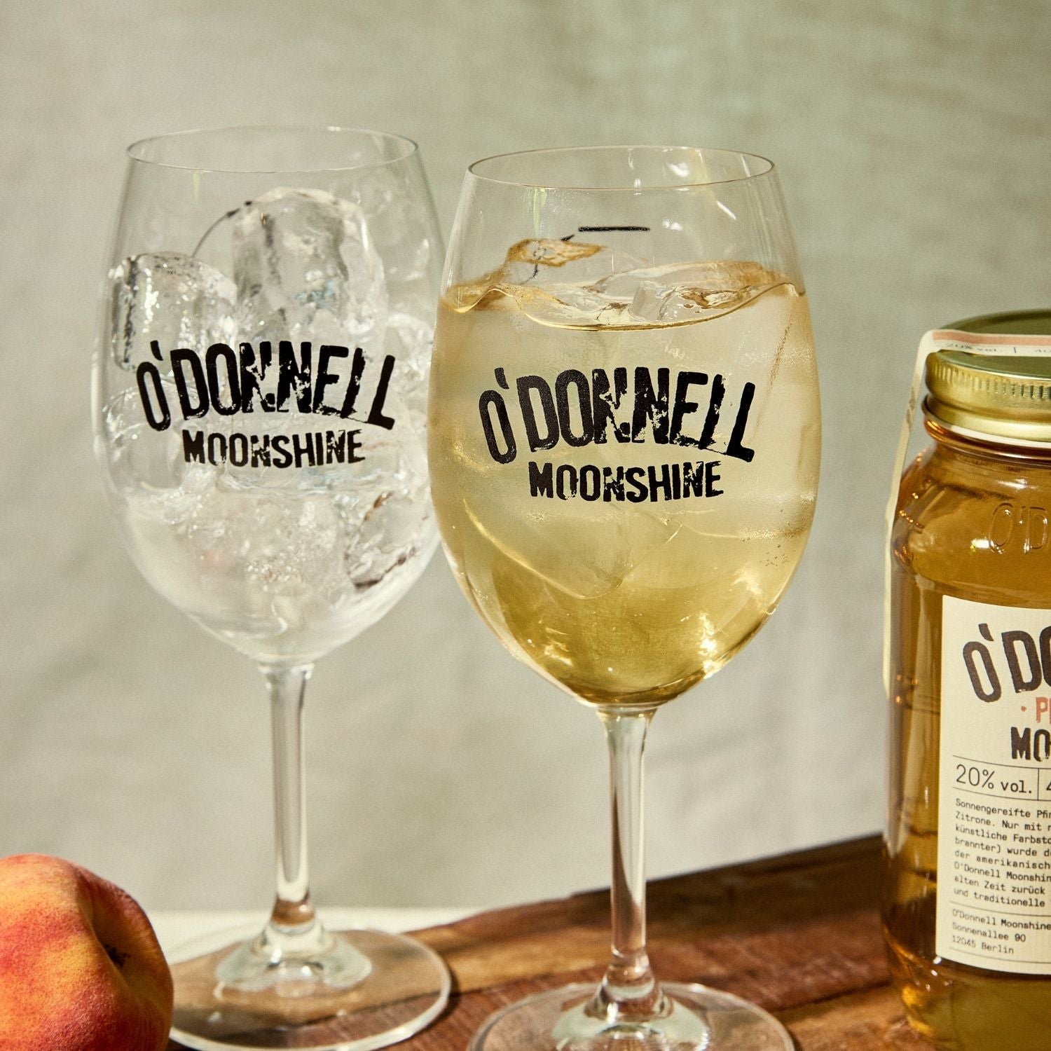 Two O'Donnell Sprit Glasses next to 2 700ml Jars of Peach Moonshine and a pouring lid