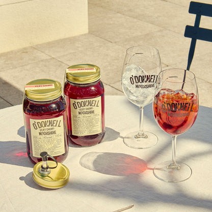 Two O'Donnell Sprit Glasses next to 2 700ml Jars of Very Cherry Moonshine and a pouring lid