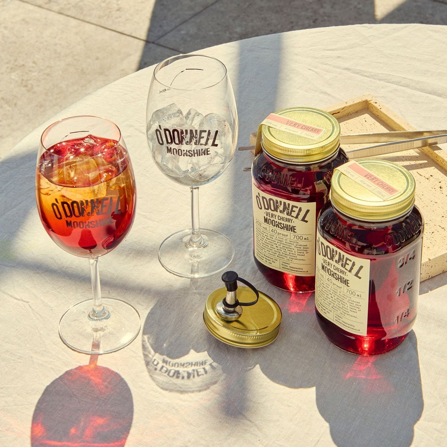 Two O'Donnell Sprit Glasses next to 2 700ml Jars of Very Cherry Moonshine and a pouring lid