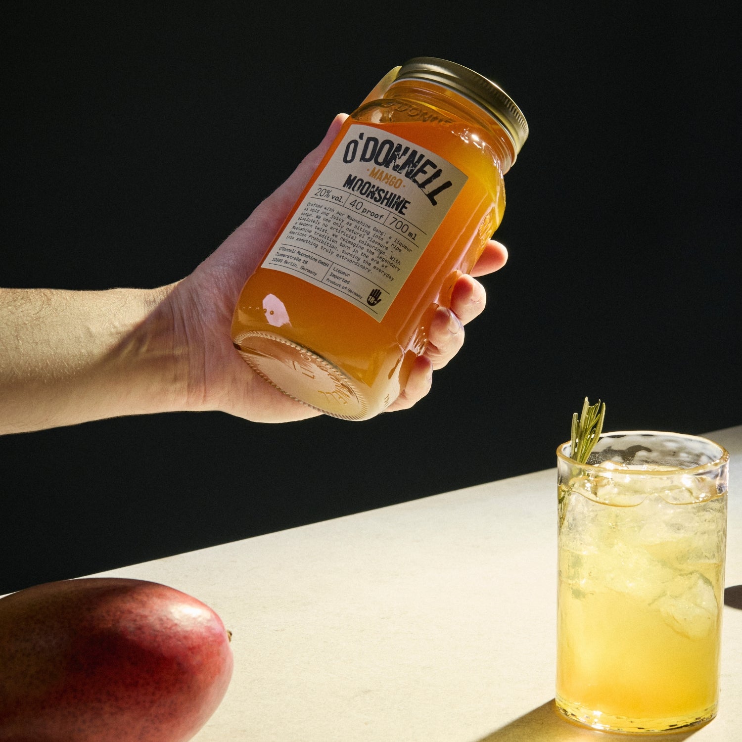 A hand holding a Mango Liqueur jar