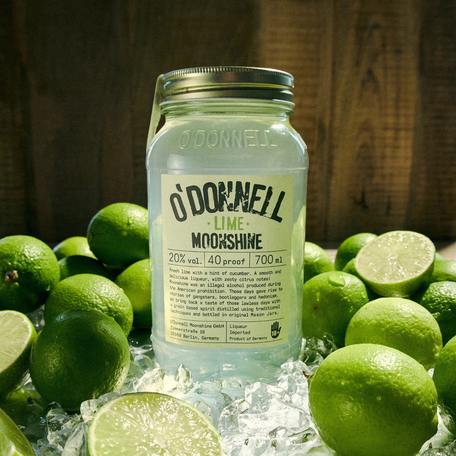 O'Donnell Lime Moonshine Jar  surrounded by limes on a wooden surface