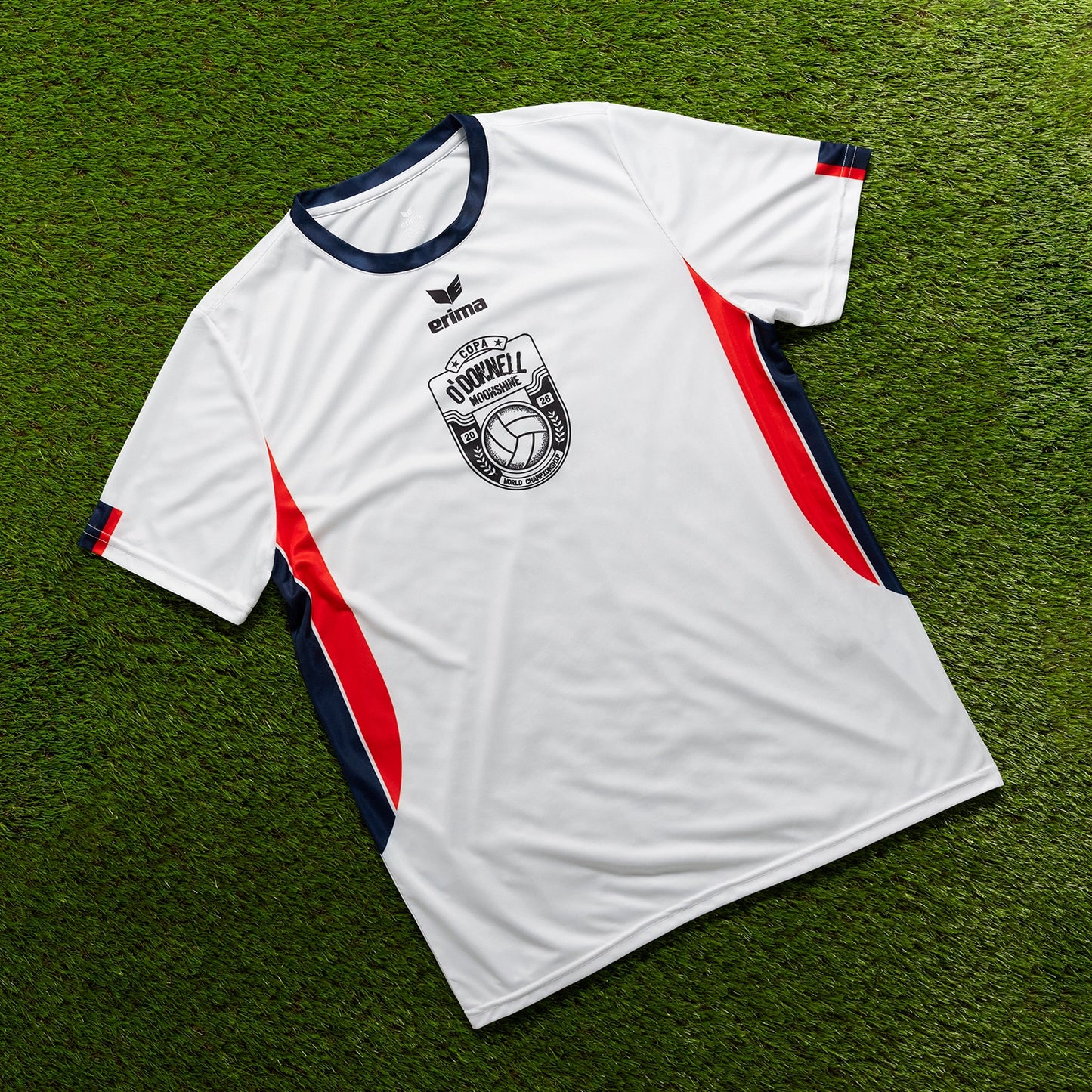 O'Donnell Moonshine WM Football Jersey – white jersey with navy collar and orange side stripes, flat lay on grass