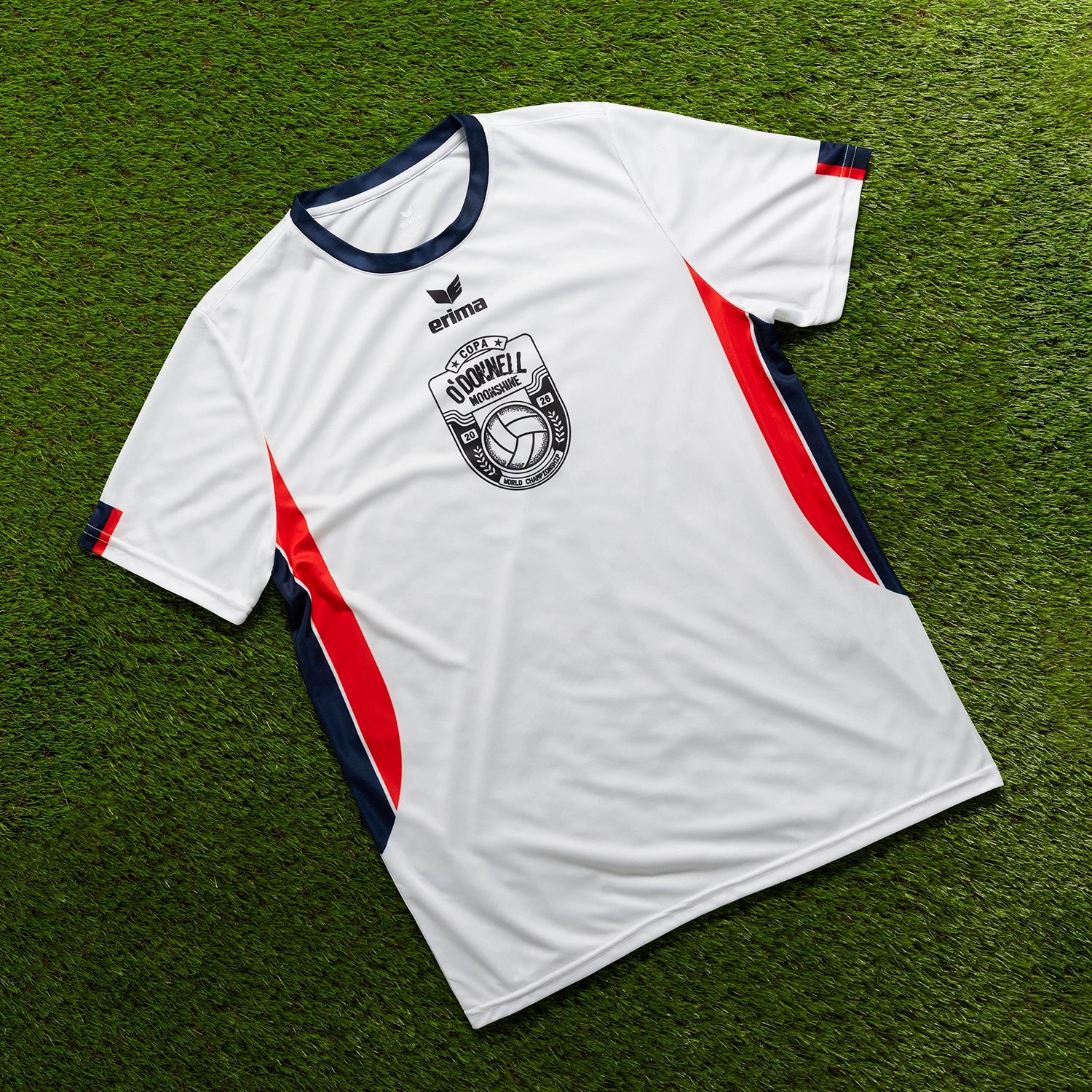 O'Donnell Moonshine WM Football Jersey – white jersey with navy collar and orange side stripes, flat lay on grass