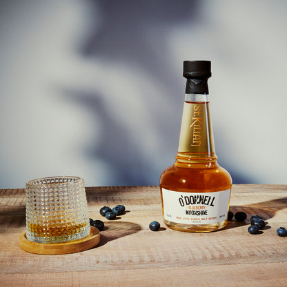 bottle of blueberry moonshine whisky with a glass on a wooden surface