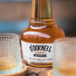 Bottle of O'Donnell Blueberry Moonshine with two glasses on a wooden surface.
