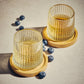 Two Textured Tumbler Glasses on a wooden coaster. Surrounded by blueberries