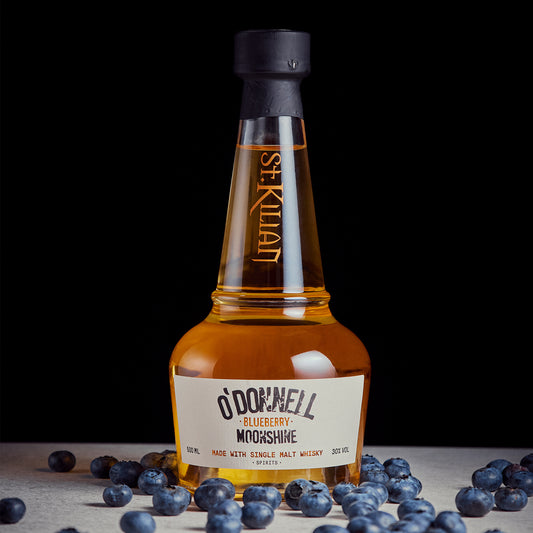 Blueberry Moonshine x Whiskey bottle on a dark background surrounded by blueberries