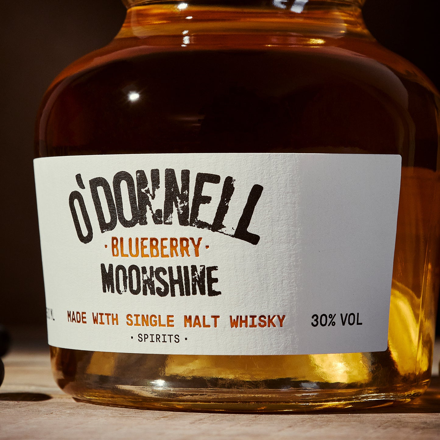 Bottle of O'Donnell Blueberry Moonshine with a label on a wooden surface.