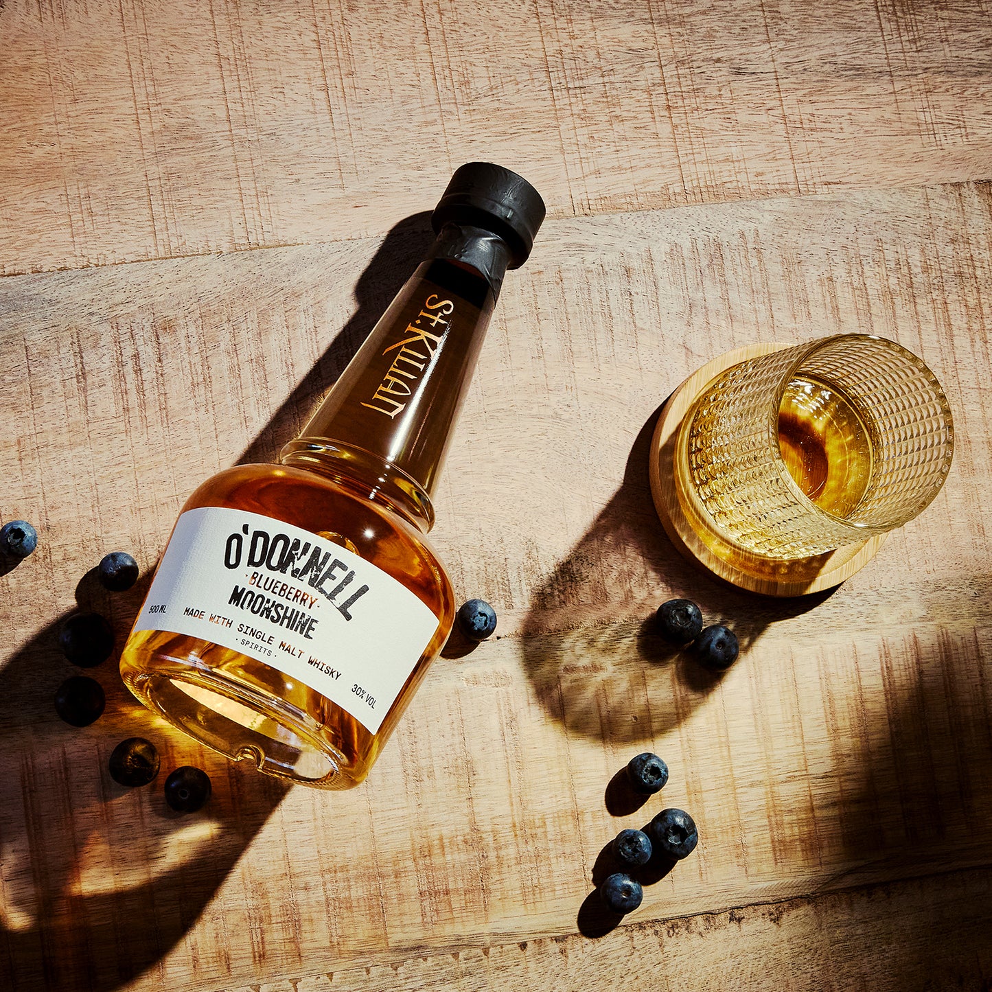 Bottle of O'Donnell blueberry moonshine whiskey with a glass on a wooden surface