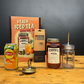 Collection of peach-themed items including a can, bottles, and a cocktail book on a wooden surface.