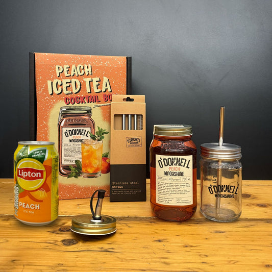 Collection of peach-themed items including a can, bottles, and a cocktail book on a wooden surface.