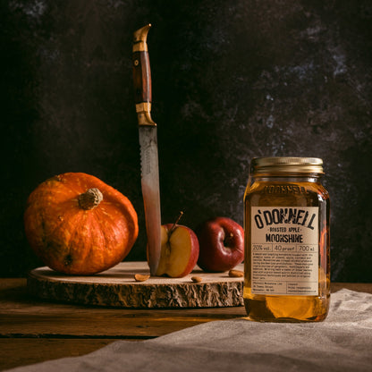 Roasted apple moonshine with chopping board, squash and apples