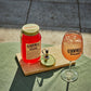 A blood Orange moonshine 700l Jar next to a O'Donnell Moonshine Spritz glass and a pouring lid.