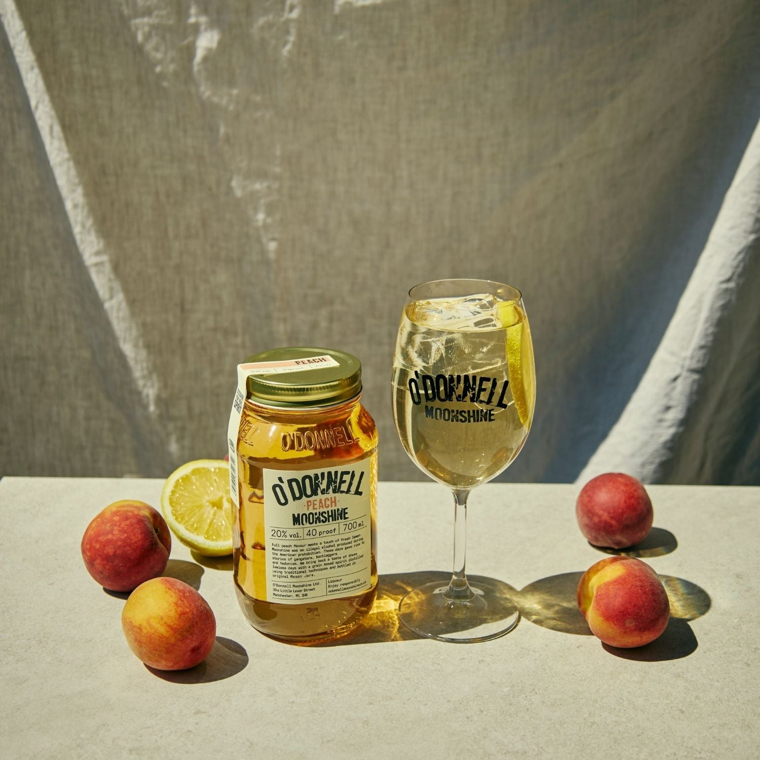 A Peach moonshine 700l Jar next to a O'Donnell Moonshine Spritz glass 