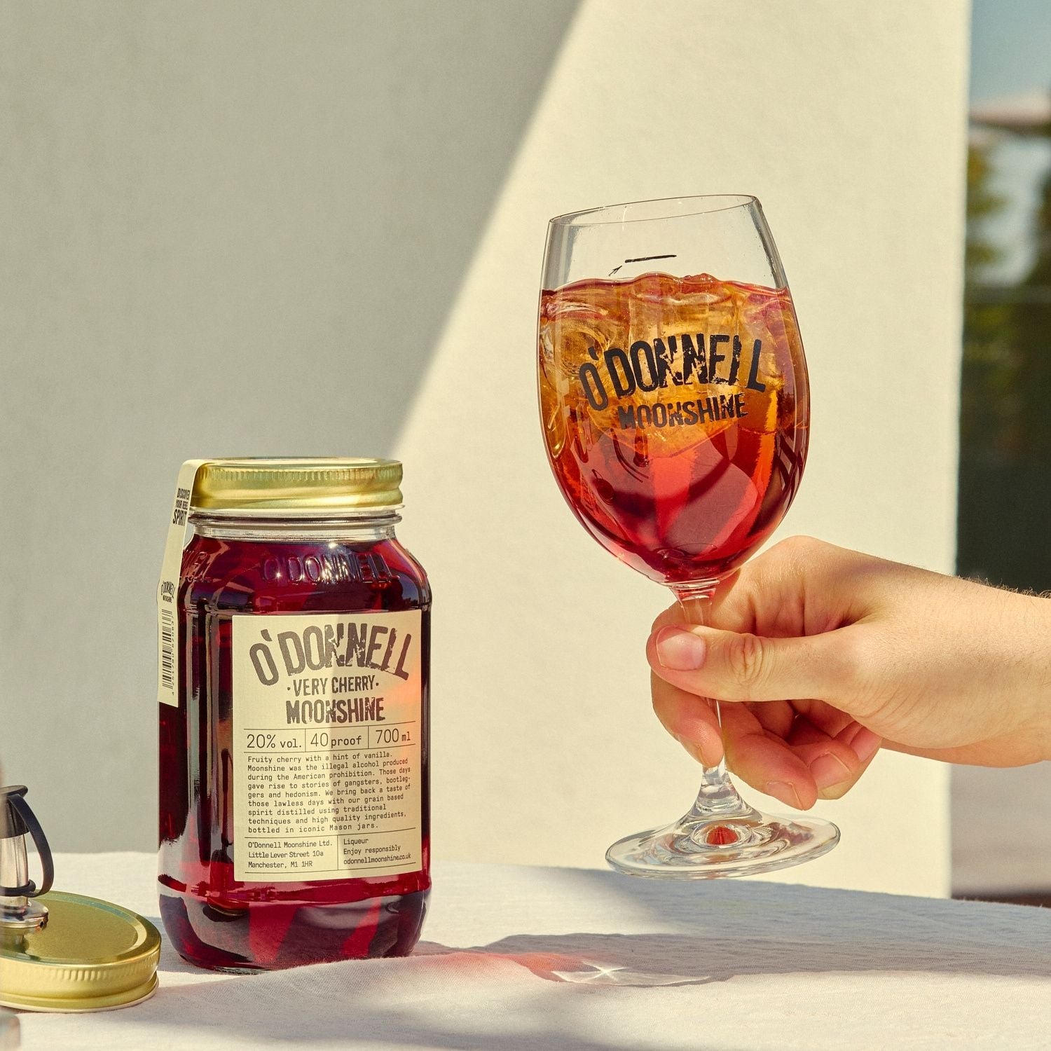 A Very Cherry moonshine 700l Jar next to a O'Donnell Moonshine Spritz glass 