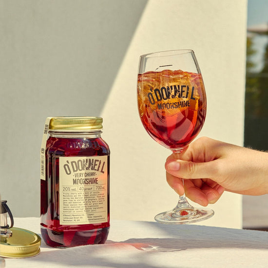 A Very Cherry moonshine 700l Jar next to a O'Donnell Moonshine Spritz glass 