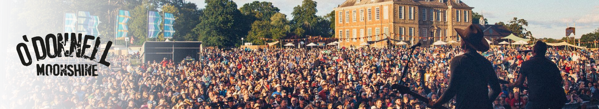 Large crowd at an outdoor event with a building in the background, featuring O'Donnell Moonshine branding.