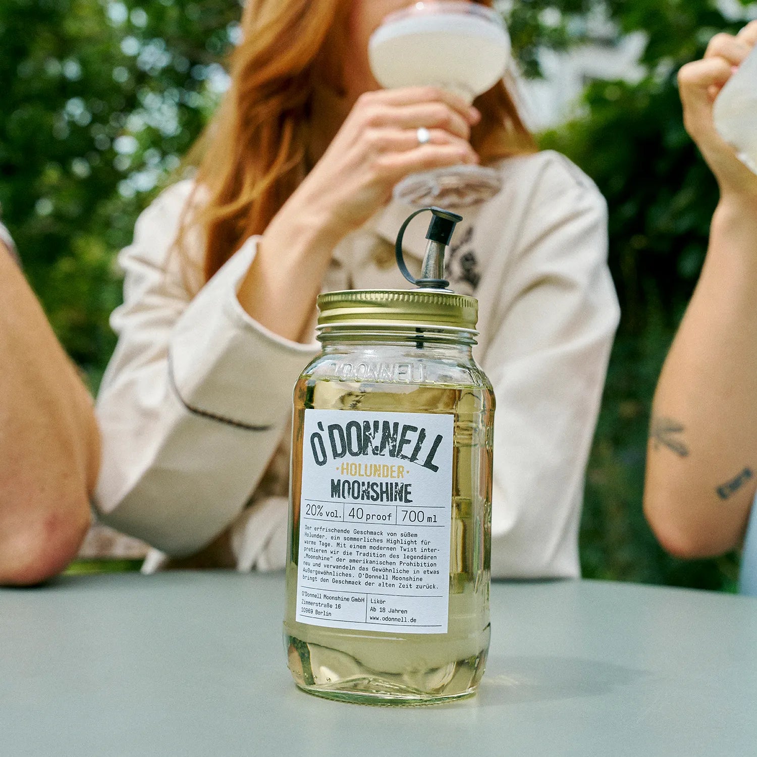 O'Donnell Moonshine Elderflower Liqueur, with a Mason jar in front of a group enjoying it as a cocktail.