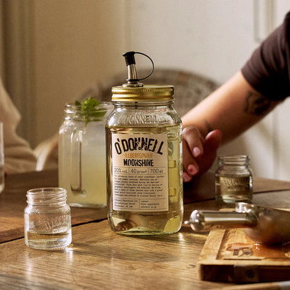 O'Donnell Moonshine elderflower liqueur, with a Mason jar in front of a prepared cocktail.