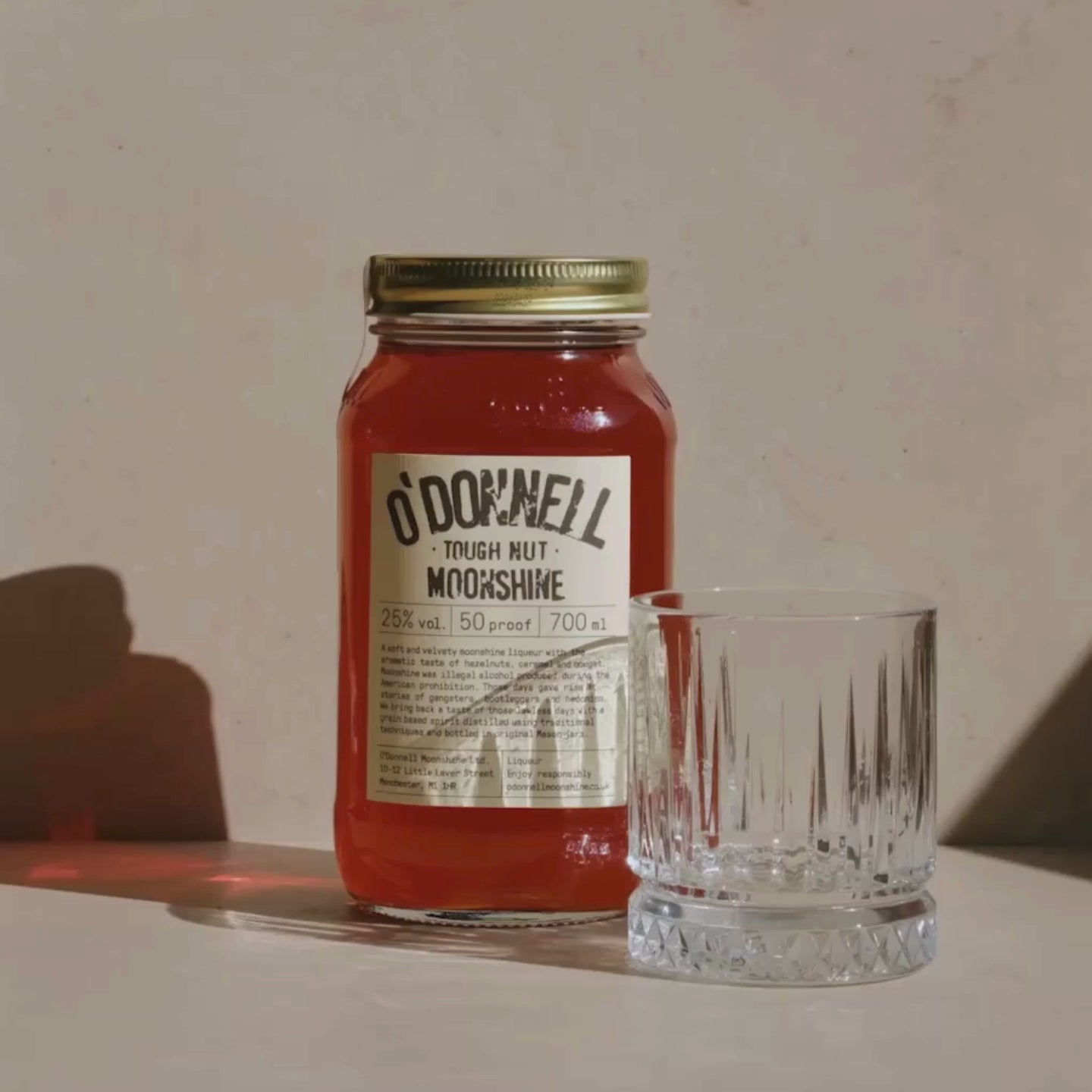 Tough Nut moonshine being poured from a 700ml jar into a small tumbler glass